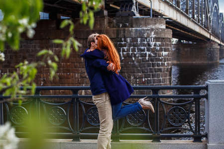 Man holding redhead woman. Scene near train bridge and river.の写真素材