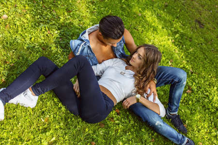 Beautiful young couple lying on grass field.の写真素材