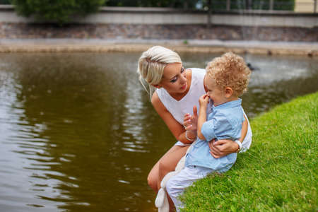 Blond female relaxing with her child in a park.の写真素材