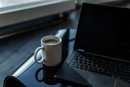 Morning cup of coffee and working space with laptop.の写真素材