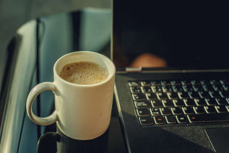 Morning cup of coffee and working space with laptop.の写真素材