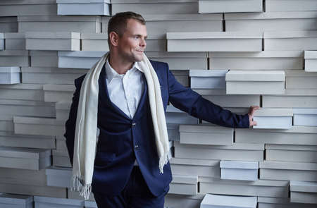 Man in blue suit posing over white artistic wall from bricks.の写真素材