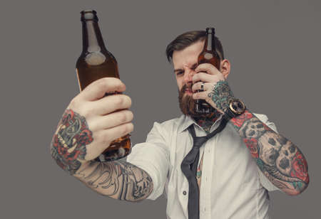 Tattooed man in white shirt holds two bear bottles. Isolated on grey backgroundの写真素材