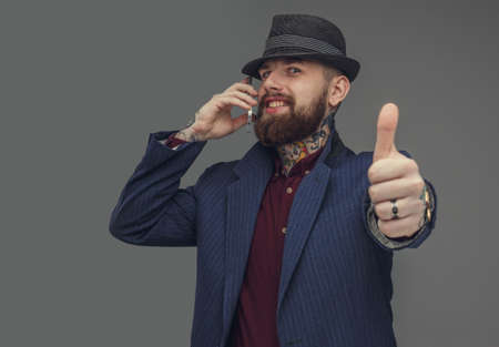 Bearded man in blue suit talking by smartphone. Isolated on grey background.の写真素材