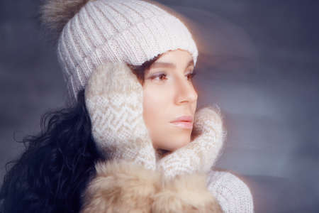 Portrait of brunette woman in warm winter hat and fur gloves.の写真素材