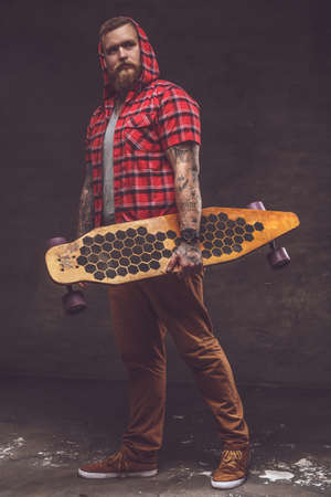 Bearded man in red shirt holds longboard.の写真素材