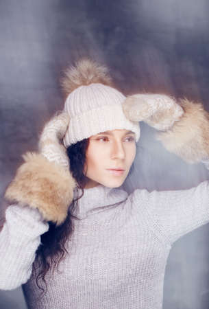 Portrait of cute brunette woman in white pulover and winter hat.の写真素材