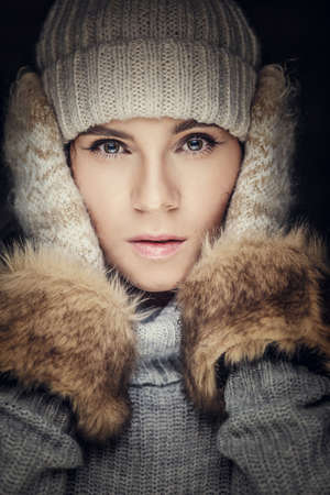 Close up portrait of woman in winter hat and fur gloves.の写真素材