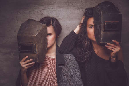 Two women with welder masks.