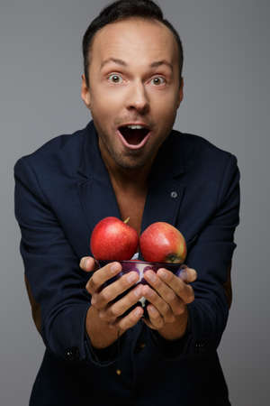 Mickey man in blue suit holding red apples.の写真素材