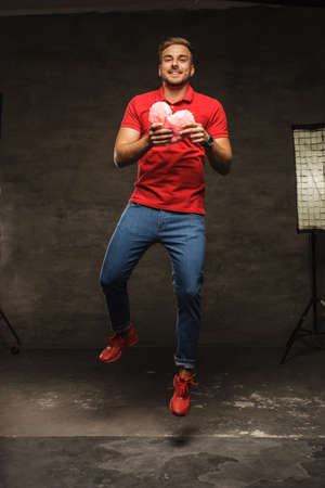 Handsome smiling jumping guy with heart in his arms.の写真素材