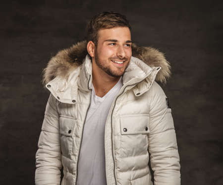 Smiling young man in winter warm coat with fur hood.の写真素材