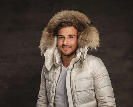 Smiling fashionable man in winter white coat with fur hood.の写真素材