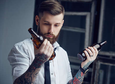 Drunk hipster man with tattoes holding empty beer bottles.の写真素材
