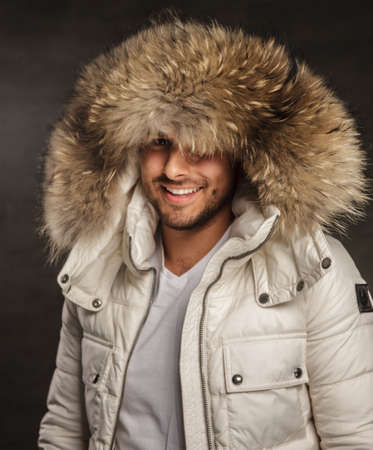 Smiling young man in winter warm coat with fur hood.