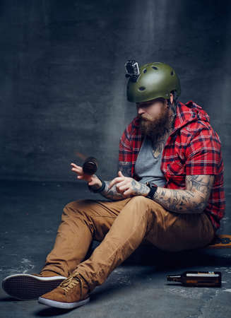 Bearded man in red shirt sitting on long board.の写真素材