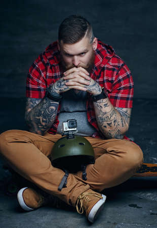 Bearded man in red shirt holding longboard skateboard.の写真素材