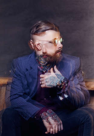 Fashionable bearded man in sunglasses posing on camera.