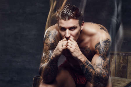 Thinking muscular guy with tattooes on his body.の写真素材