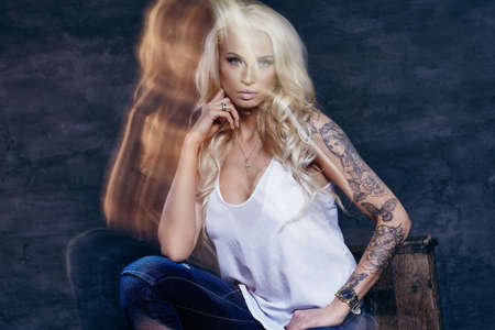 Gorgeous female in denim jeans with blond curly hair.の写真素材