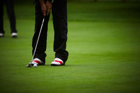 Golf player's legs on green field.の写真素材