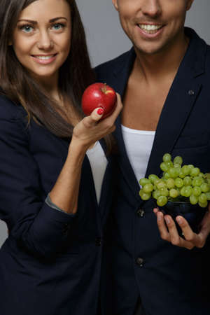 Smiling man and woman holding fruits in their arms.の写真素材
