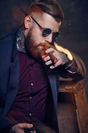 Bearded fashionable man in sunglasses smoking cigar.の写真素材