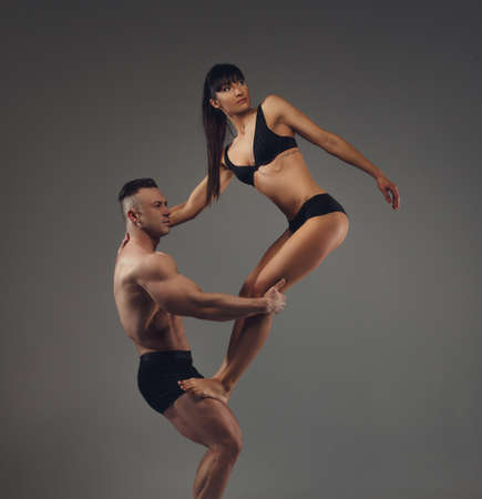 Shirtless muscular man holding slim brunette woman on his knees. Isolated on grey background.の写真素材