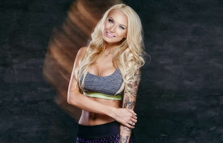 Smiling blond fitness woman with tattoo on her arm.の写真素材