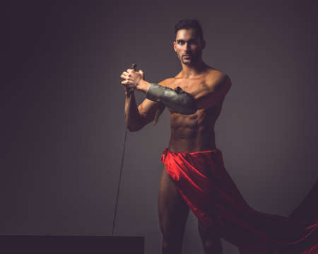 Artistic image with naked muscular man in a red fluttering dress.の写真素材