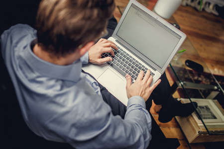 A man in a grey shirt working on laptop.の写真素材