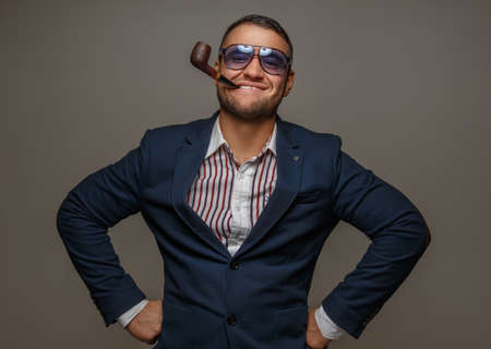 A man in sunglasses and in a suit smoking pipe.の写真素材