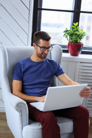 A student sitting on the chair and working with laptop.