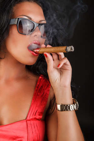 Brunette woman in sunglasses smoking a cigar.の写真素材