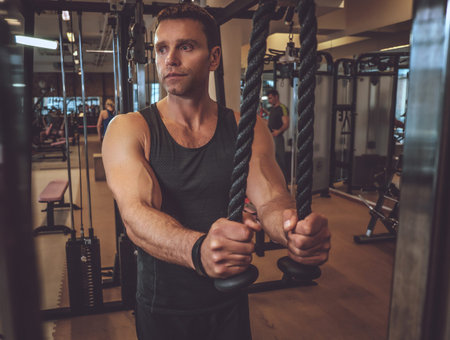 Muscular man doing triceps exercise in a gym club.