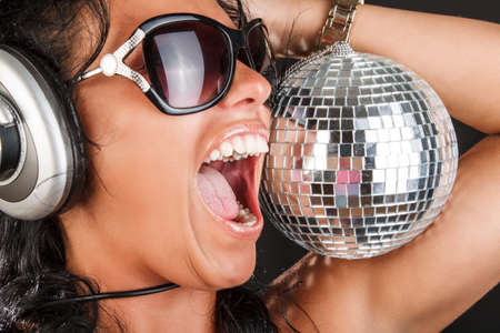 A woman in sunglasses holds mirror disco ball.の写真素材