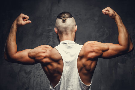 Muscular man's back on a grey background.