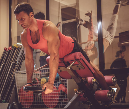 Middle age man doing workouts in a gym club.