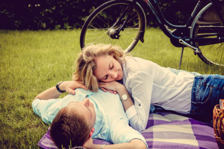 Casual young couple relaxing on a lawn after bike riding.の写真素材