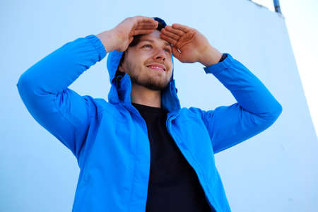 Positive man in blue hoodie looking up.の写真素材