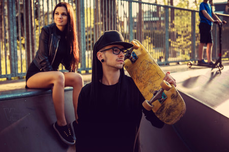 Tattooed skater and his girlfriend in skate park.