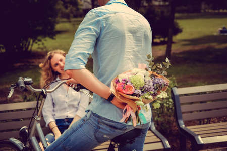 Surprise flower bouquet from casual man on a bicycle to cute blond woman.の写真素材