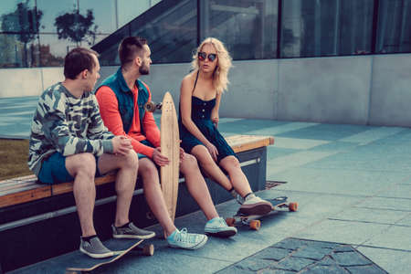 Two males and one female with longboards posing on the street in urban style.の写真素材