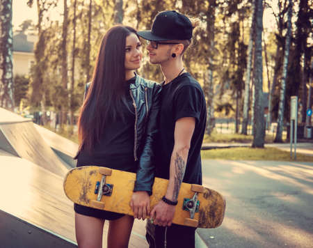 Tattooed skater and his girlfriend in skate park.の写真素材