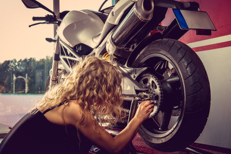 Sexy blond female repairing motorbcycle in a garage.