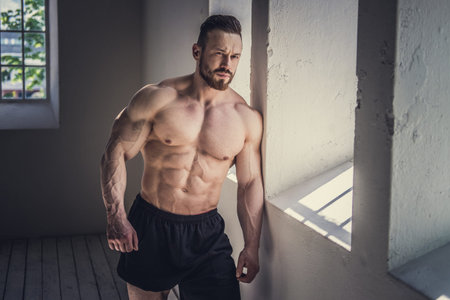 Shirtless bodybuilder posing in natural light.