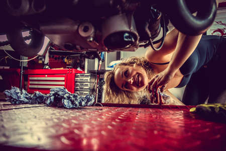 Blond female mechanic repairing motocycle engine.の写真素材