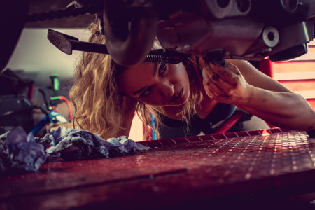 Blond female mechanic repairing motocycle engine.の写真素材