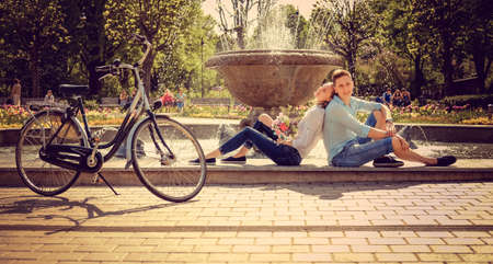 Casual couple relaxing near fountain after bicycle riding.の写真素材