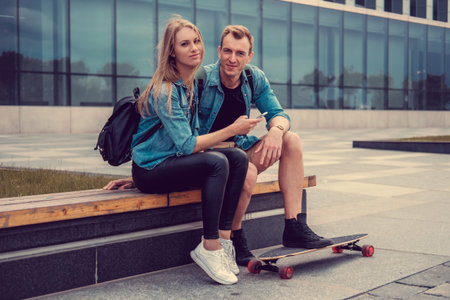 Casual couple with longboard posing on a square in a city.の写真素材